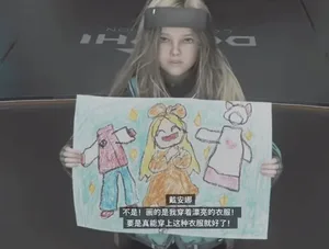 游戏《识质存在》截图:角色戴安娜坐在桌前,手持画笔和画纸,纸上绘有她身穿DLC服装的简笔画,她面带天真表情望向画面外。