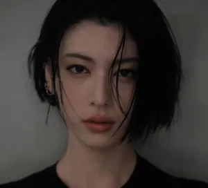 日本演员三吉彩花身穿冷色调黑色露背长裙,短发干练,背部可见水墨风格蓝色花卉纹身沿脊柱纵向延伸,画面聚焦其上半身后侧,背景简洁。