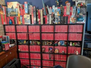 一张室内照片,展示满墙满架的Nintendo Switch实体游戏卡带盒,排列密集整齐,包含多种封面设计和收藏版包装,背景可见部分家居环境。