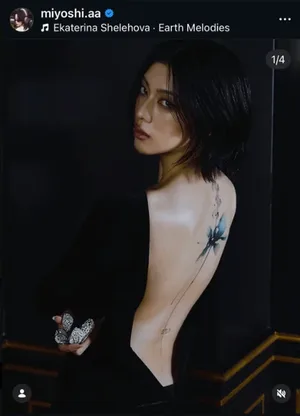 日本演员三吉彩花身穿冷色调黑色露背裙,短发,背部有沿脊柱延伸的水墨风格蓝色花卉纹身,画面聚焦其背部纹身与整体造型。