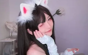Coser‘一颗小兔娘’身着白色系洛丽塔风格服装，佩戴兔耳发饰，面带微笑面对镜头，背景为浅色简约室内环境。