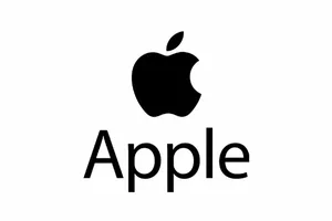 苹果公司CEO蒂姆·库克与即将接任的CEO约翰·特努斯并肩站在史蒂夫·乔布斯剧院舞台上,背景为苹果标志性的环形建筑内景,两人均着深色西装,面带微笑。