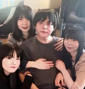一名中年日本男性身穿蓝色酒店保洁制服,手持拖把站在一间整洁但普通的酒店卫生间内,面露疲惫神情,背景可见洗手台和马桶。