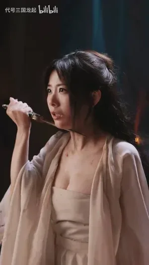 游戏《代号三国：龙起》截图：演员钱思怡饰演的角色邹素被绑在木桩上，身穿古风服饰，面部表情凝重，身上可见浅色伤痕，背景为昏暗室内场景。