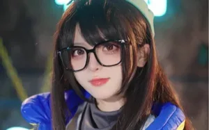 Coser‘一颗小兔娘’身着粉色系洛丽塔风格服装，站在室内布景前微笑比耶，背景可见浅色帷幔与柔光灯效，妆容精致，发型为双马尾配蝴蝶结发饰。