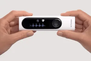 Withings BeamO 四合一健康扫描仪实物图,白色手持设备,正面可见圆形传感器区域、LED指示灯及品牌logo,置于浅灰色背景上