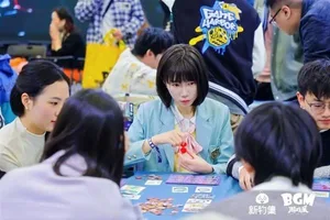 新物集BGM游戏展上海站现场,多人围站在一个摆放潮玩与解压捏捏的展台前观看或挑选,背景可见展会标识和人群流动的室内展厅环境。