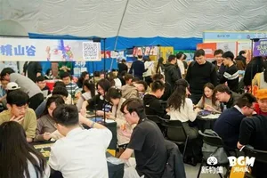 新物集BGM游戏展上海站现场照片:多人围站在一个布置有灯光和品牌标识的展台前,部分人手持手机拍摄,背景可见其他参展观众和展陈设施。