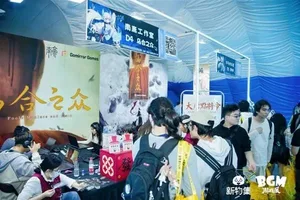 新物集BGM游戏展上海站现场照片:多人围站在一个布置有品牌标识的展台前,部分观众低头专注试玩独立游戏,展台屏幕上显示游戏画面,背景可见其他参展观众和展陈设施。